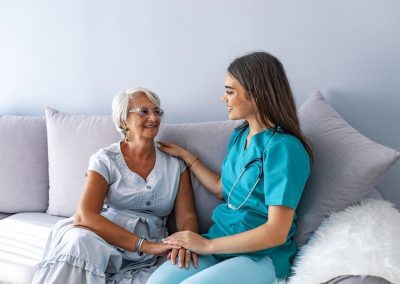 Young nurse spending time with happy elder patient in nursing home